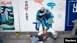资料照：一名农民工在北京火车站的一个中国梦的政府宣传牌下打盹。