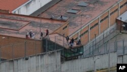 Prisoners stand on the roof of the Turi jail where dozens of prison guards and police officers were kidnapped by inmates in Cuenca, Ecuador, Aug. 31, 2023. Ecuadorian authorities announced Friday the release of the guards and police.
