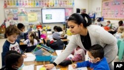 Christine Ramroop, who graduated from Bowie State University in 2020, teaches first graders during their warm-up for the day at Whitehall Elementary School, Tuesday, Jan. 24, 2023, in Bowie, Md.