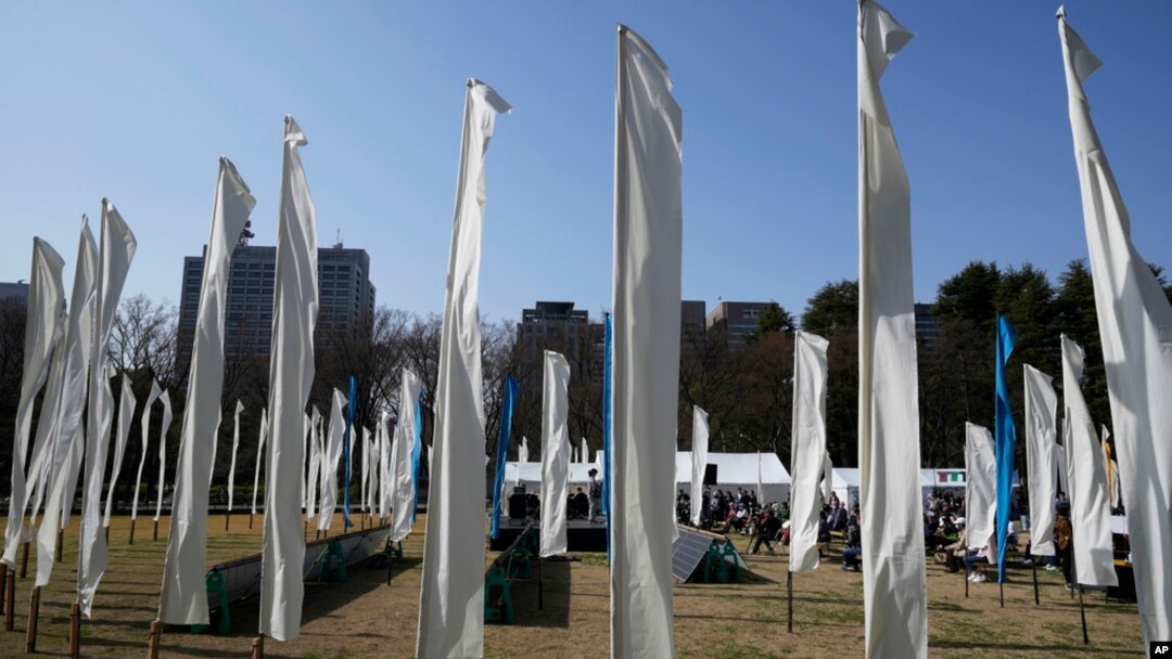 Artists perform on stage surrounded by decorations of 'peace flags' to commemorate victims of the earthquake and tsunami in the Tohoku region 12 years ago, during an anniversary event at Hibiya Park in Tokyo, March 11, 2023.