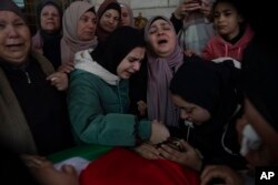 Huda Qatawi, center and family members cry while they take the last look at the body of her son Hazem Qatawi, 23 during his funeral in the West Bank city of Beitunia, Dec. 28, 2023.