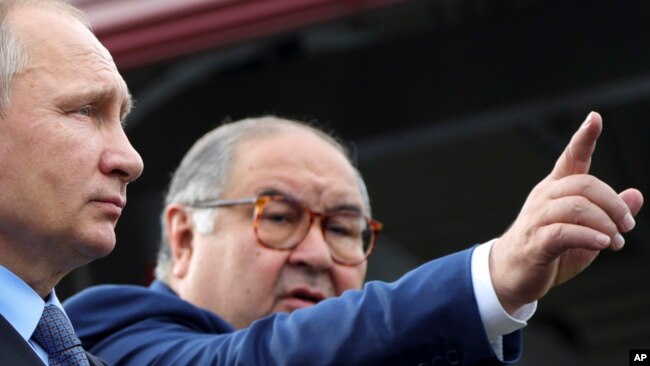 FILE - Russian businessman and close ally of President Vladimir Putin Alisher Usmanov points while speaking Putin, left, at the Lebedinsky GOK mining plant, in Gubkin, Belgorod region, Russia, July 14, 2017. (Mikhail Klimentyev, Sputnik, via AP)