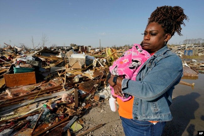 Wonder Bolden acuna a su nieta de un año, Journey Bolden, mientras examina los restos de la casa móvil demolida por un tornado de su madre en Rolling Fork, Mississippi, el sábado 25 de marzo de 2023.