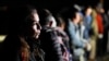 ARCHIVO - Una mujer de Cuba espera con otros migrantes para ser procesados para buscar asilo después de cruzar la frontera hacia Estados Unidos, el 6 de enero de 2023, cerca de Yuma, Arizona.