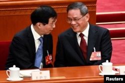 China's newly-elected Premier Li Qiang (R) is congratulated by Chinese People's Political Consultative Conference Chairman Wang Huning at the Great Hall of the People, March 11, 2023. (Greg Baker/Pool via Reuters)