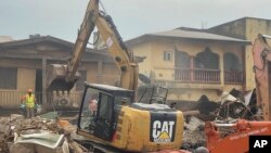 A digger removes debris from the site of a collapsed building in Abuja, Nigeria, Aug. 24, 2023. The building collapsed on Wednesday night, killing two people with many feared trapped inside. 