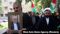 Seorang pria tampak membawa foto pemimpin Hamas, Ismail Haniyeh, menyusul pembunuhan terhadapnya, dalam sebuah aksi massa di Teheran, Iran, pada 31 Juli 2024. (Foto: Majid Asgaripour/WANA (West Asia News Agency) via Reuters)