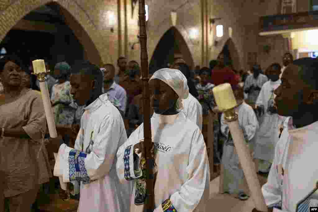 An altar girl carries a crucifix during a Christmas Mass at our Lady of the Congo Cathedral in Kinshasa on December 24, 2023.&nbsp;