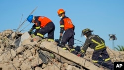 Rescue personnel search the site of a building collapse in George, South Africa, May 9, 2024. 