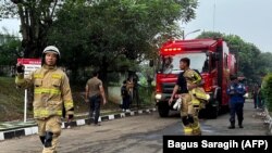 Petugas pemadam kebakaran keluar setelah memadamkan api di pintu masuk gudang amunisi militer tempat beberapa ledakan terjadi di Gunung Putri, Jawa Barat, pada 31 Maret 2024. (Foto: Bagus SARAGIH/AFP)