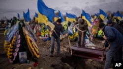 Cemetery workers bury the coffin of Oleksii Lytvynov, 29, during his funeral in Brovary, near Kyiv, Feb. 19, 2023. Lytvynov, a civilian who joined the Ukrainian Armed Forces, was killed on Feb. 11, during battle for Vuhledar in the southeast of the country.