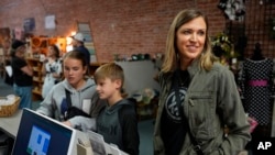 FILE - Kristina McGuffey with her 12-year-old daughter, Molly, and 9-year-old son, Wyatt, speaks while making a purchase at a downtown craft collective May 21, 2024, in Greeley, Colo.