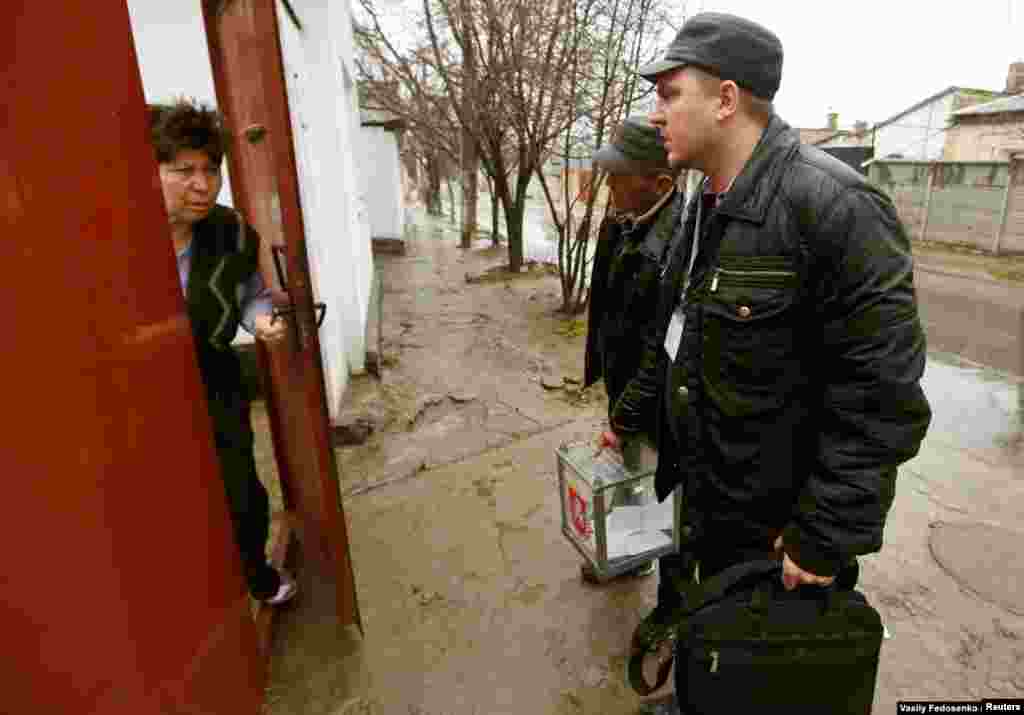 Los funcionarios electorales de las autoridades de Crimea instaladas por Rusia llegan a una casa en Simferopol con una urna móvil durante la votación del referendo del 16 de marzo. El referendo no ofrecía la opción de que Crimea mantuviera su status quo. Fue declarado ilegal por Kiev y no reconocido por la mayoría de los países.