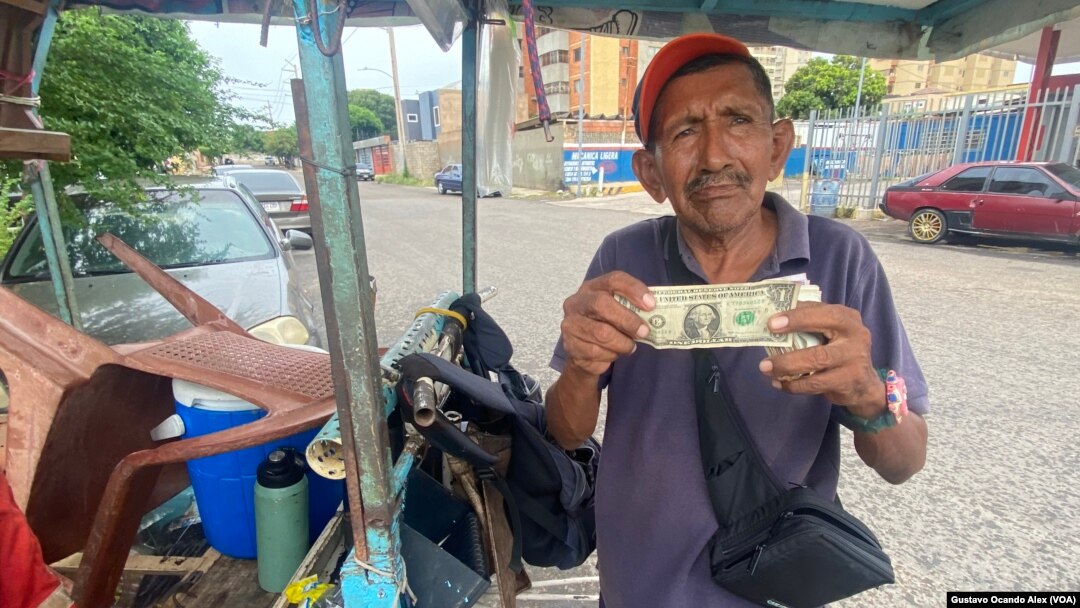 Un vendedor ambulante de golosinas y cigarros muestra un billete de un dólar estadounidense en Maracaibo, Venezuela.