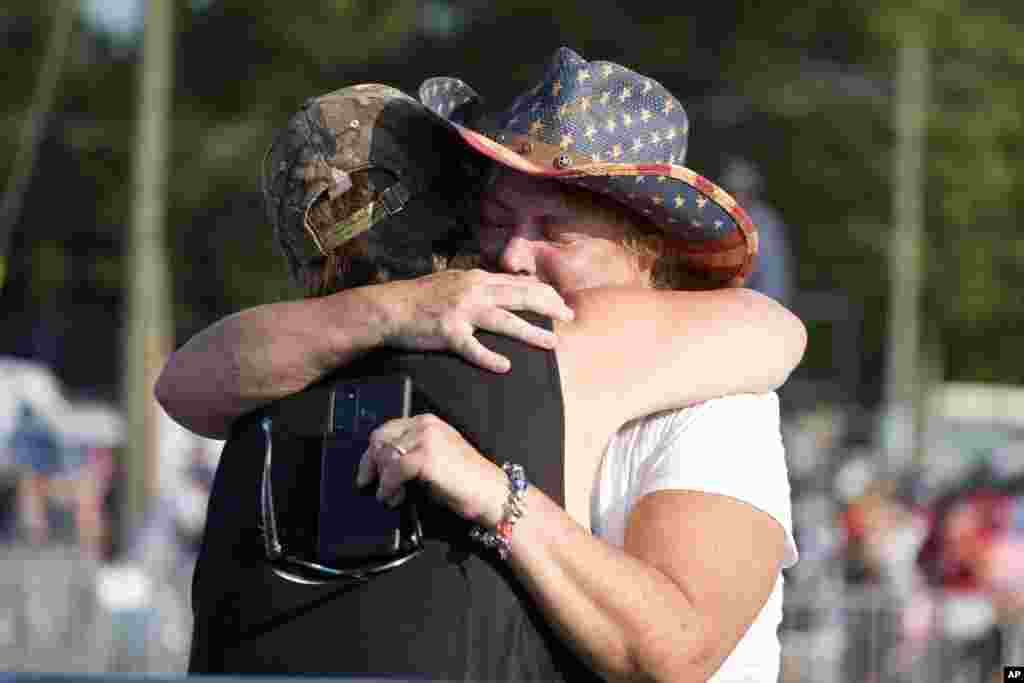 People hug after Donald Trump was taken from the venue.