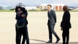 French journalist Olivier Dubois, left, who was held hostage in Mali for nearly two years, is welcomed by loved ones and French President Emmanuel Macron, second from right, upon his arrival at an airport near Paris on March 21, 2023. 
