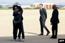 French journalist Olivier Dubois, left, who was held hostage in Mali for nearly two years, is welcomed by family members and French President Emmanuel Macron, second from right, upon his arrival at the Villacoublay airport near Paris, on March 21, 2023.