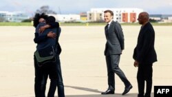 French journalist Olivier Dubois, left, who was held hostage in Mali for nearly two years, is welcomed by loved ones and French President Emmanuel Macron, second from right, upon his arrival at an airport near Paris on March 21, 2023. 
