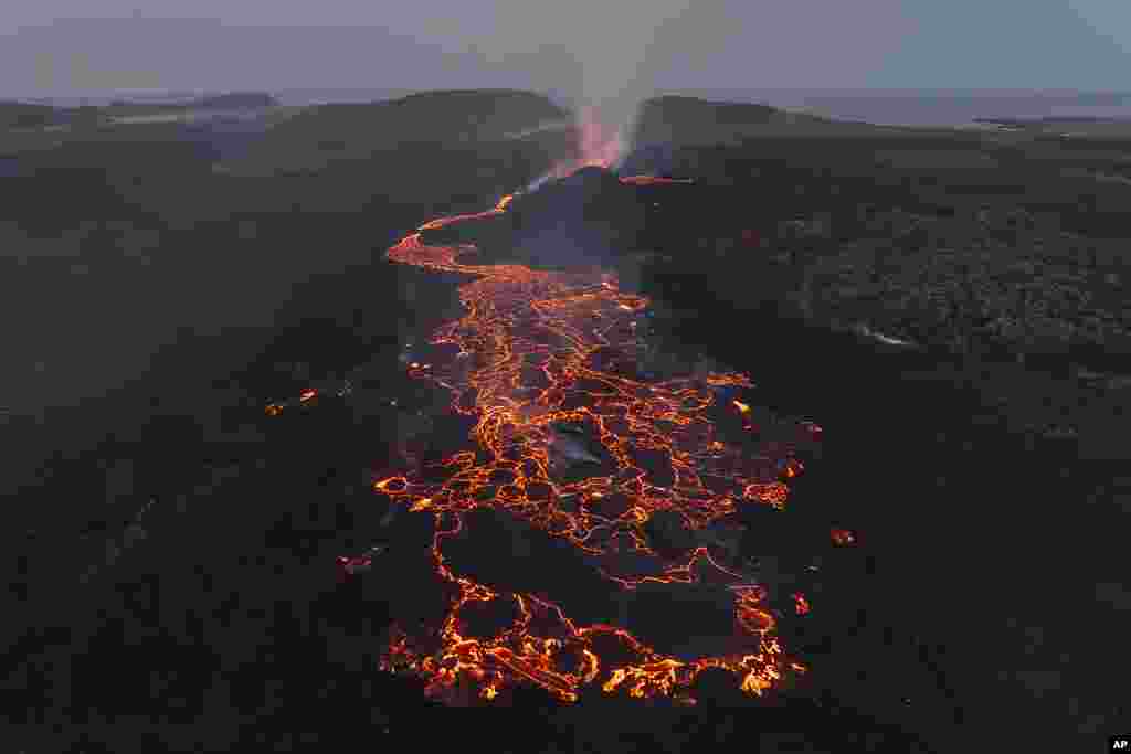 Red lava spews from an erupting volcano near Grindavik, Iceland.