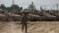 Israeli soldiers work on tanks at a staging ground near the border with the Gaza Strip, in southern Israel, April 11, 2024.
