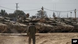 2024年4月11日，以色列士兵在以色列南部加沙地带边境附近的一个集结地修理坦克。