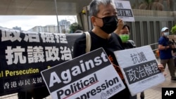 FILE - Pro-democracy activist Lee Cheuk-yan, center, holds placards as he arrives at a court in Hong Kong, April 1, 2021. Hong Kong national security police arrested, March 9, 2023, Lee's wife Elizabeth Tang, herself a labor activist, after visiting her husband in prison.
