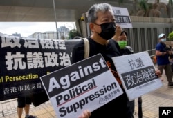 资料照：香港前“支联会”秘书长李卓人在他抵达香港一家法院前举牌抗议。（2021年4月1日）