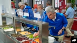 IOC President Thomas Bach tries food from a salad bar while touring the Olympic Village ahead of the 2024 Summer Olympics, July 22, 2024, in Paris, France. 