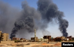 FILE: A man walks while smoke rises above buildings after aerial bombardment, during clashes between the paramilitary Rapid Support Forces and the army in Khartoum North, Sudan, May 1, 2023.