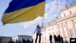 (FILE) A woman waves a Ukrainian flag as she attends a protest in Germany.