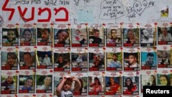 ဟာမတ်စ်အဖွဲ့က ဖမ်းဆီးသွားတဲ့ ဓားစာခံများရဲ့‌ဓာတ်ပုံရှေ့ လမ်းသွားလမ်းလာကလေးငယ်တဦးကို တွေ့ရစဉ်။ (ဧပြီ ၂၃၊ ၂၀၂၄) Tel Aviv မြို့၊ အစ္စရေး