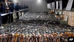 In this photo provided by the Serbian Presidential Press Service, Serbian President Aleksandar Vucic, left, inspects weapons collected as part of an amnesty near the city of Smederevo, Serbia, May 14, 2023.