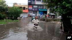A motorcyclist drives through a road flooded by heavy rain in Peshawar, Pakistan, July 30, 2024. 
