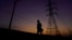 FILE - A jogger passes power lines during a sunset run, Aug. 20, 2023, in San Antonio, Texas, as high temperatures continued to stress the power grid. Residents were asked to cut back on electricity as a prolonged and punishing summer heat wave continued.