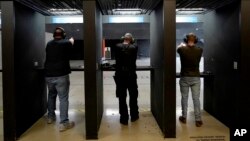 FILE - Gun owners fire their pistols at an indoor shooting range during a qualification course to renew their carry concealed handgun permits, at the Placer Sporting Club in Roseville, California, July 1, 2022.