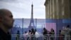 Pengunjung berjalan melewati pembatas di Trocadero dengan latar belakang Menara Eiffel di Paris, 16 Juli 2024. (JULIEN DE ROSA / AFP)