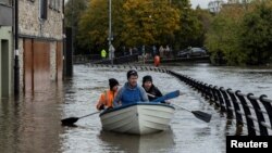 Orang-orang mendayung perahu melewati jalanan yang tergenang banjir, setelah hujan lebat menyebabkan banjir besar, menjelang datangnya Badai Ciaran, di pusat kota Newry, Irlandia Utara (31/10). 