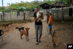 Venezuelan migrant Johany “Flaca” Rodriguez carries her dog Kiko at a shelter in Assis, Brazil, June 20, 2024.