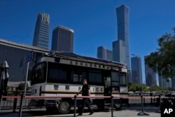 FILE - A policeman walks out from a police kiosk stationed near the Central Business District in Beijing, Aug. 22, 2023.