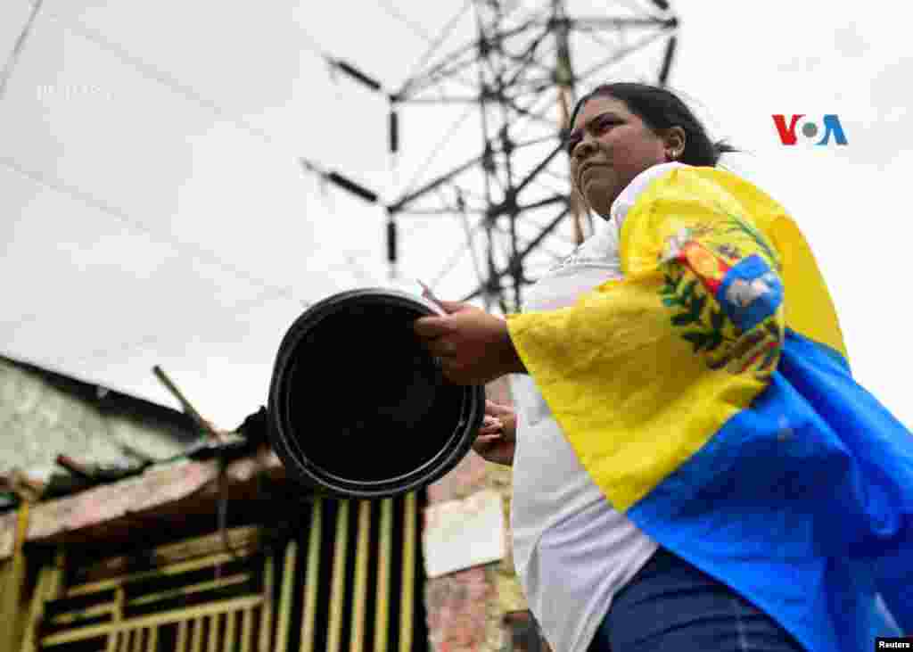 Una mujer porta una bandera de Venezuela mientras golpea una olla para protestar contra los resultados electorales.