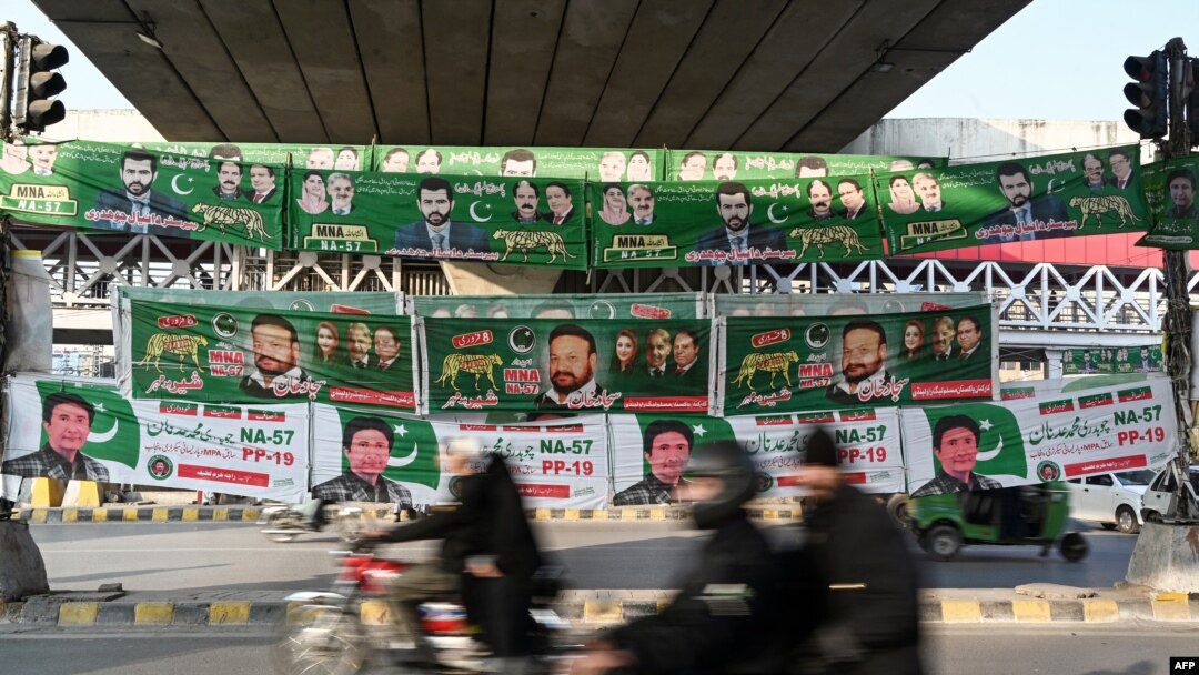 Para penumpang melewati spanduk partai politik Pakistan yang dipajang di sepanjang jalan di Rawalpindi, 15 Januari 2024, menjelang pemilihan umum. (Aamir QURESHI / AFP)
