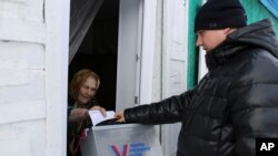 An elderly woman votes during the Russian presidential election via a mobile election committee that visits people unable to physically visit a polling station, in Nikolayevka village outside the Siberian city of Omsk, east of Moscow, Russia, March 16, 2024.