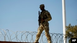 FILE - A guardsman walks over rail cars with concertina wire along the US-Mexico border, in Eagle Pass, Texas, Jan. 3, 2024. 