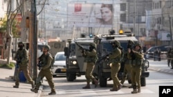 Israeli soldiers take up positions at the scene of a Palestinian shooting attack at the Hawara checkpoint, near the West Bank city of Nablus, Feb. 26, 2023.