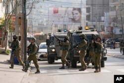 Tentara Israel di lokasi serangan penembakan Palestina di pos pemeriksaan Hawara, dekat kota Nablus, Tepi Barat, Minggu, 26 Februari 2023. (AP Photo/Majdi Mohammed)