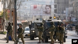 Sejumlah tentara Israel berada di lokasi insiden penembakan di Hawara, Tepi Barat, pada 26 Februari 2023. (Foto: AP/Majdi Mohammed)
