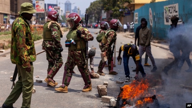 Police officers clear a bonfire blocking a road during a protest in Nairobi, Kenya, July 23, 2024.