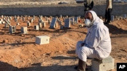 A man sits by the graves of flash-flood victims in Derna, Libya, Sept. 15, 2023. A Libyan Red Crescent official said more than 10,000 people were reported missing in the city. Health authorities previously put the death toll in Derna at 5,500.