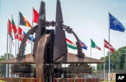 Bendera negara anggota NATO berkibar tertiup angin di luar markas NATO di Brussels, Rabu, 15 Juni 2022. (Foto: AP)