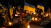 一位乌克兰女士带着女儿在乌克兰西部利沃夫的公墓悼念丈夫。(2023年2月23日)